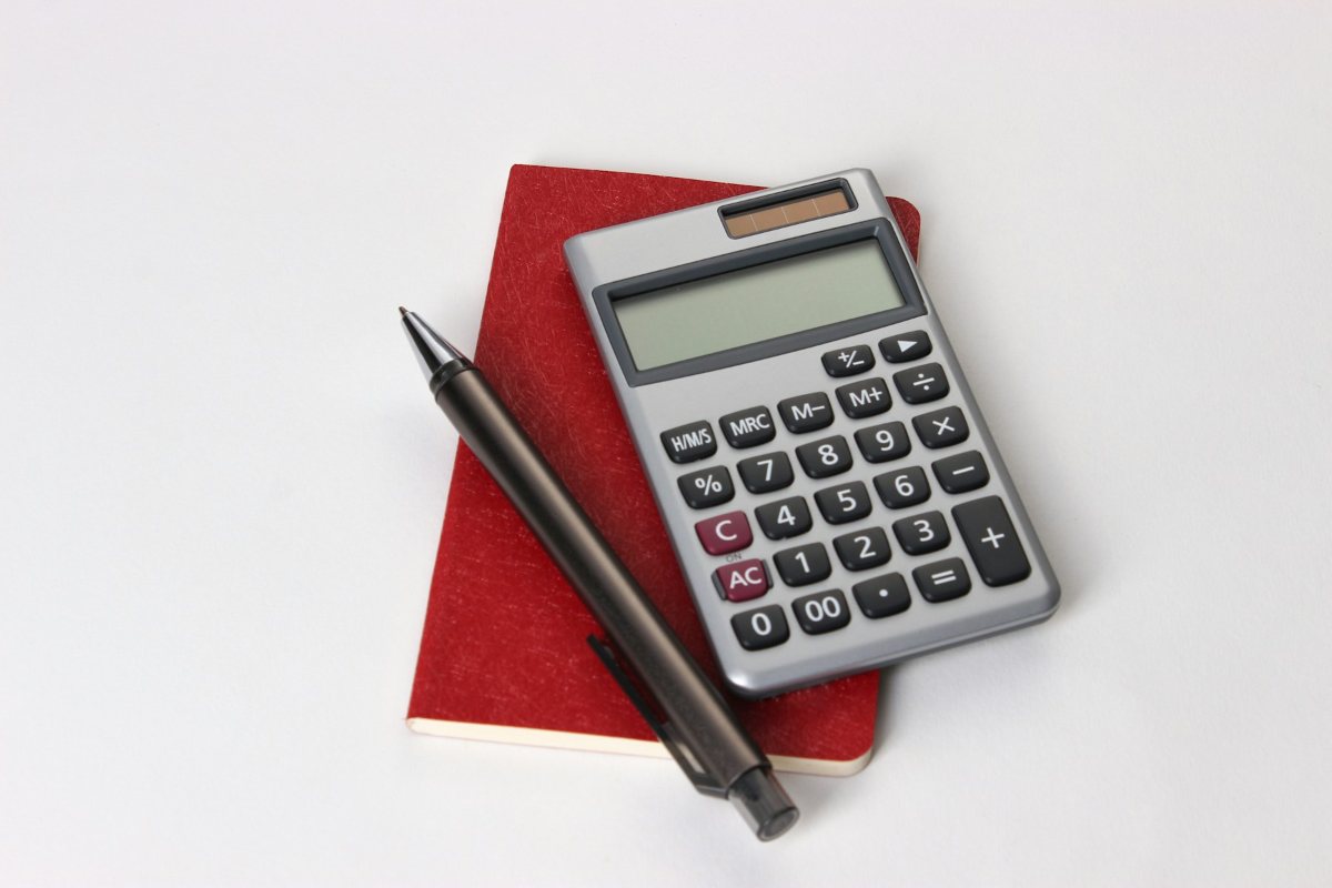 Taschenrechner mit Stift und Notizbuch – Stundenlohn berechnen